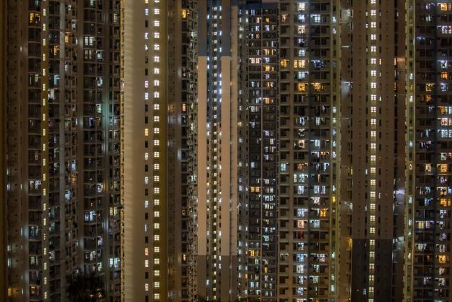 © Bloomberg. Residential buildings stand illuminated in Hong Kong, China, on Saturday, July 21, 2018. Hong Kong's property market has a habit of humbling the bears, shattering predictions that the laws of gravity must eventually prevail. Photographer: Paul Yeung/Bloomberg
