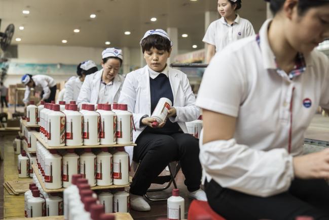 © Bloomberg. Employees arrange bottles of Moutai baijiu at the Kweichow Moutai Co. factory in the town of Maotai in Renhuai, Guizhou province, China. Photographer: Qilai Shen/Bloomberg