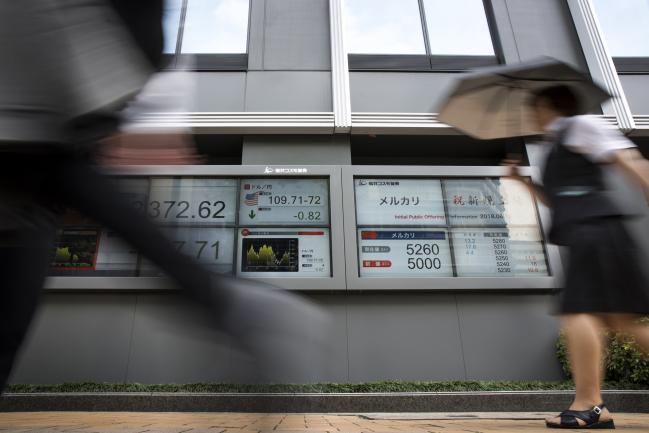© Bloomberg. Pedestrians walk past an electronic stock board displaying share prices of Mercari Inc., center right, outside a securities firm in Tokyo, Japan. Photographer: Tomohiro Ohsumi/Bloomberg