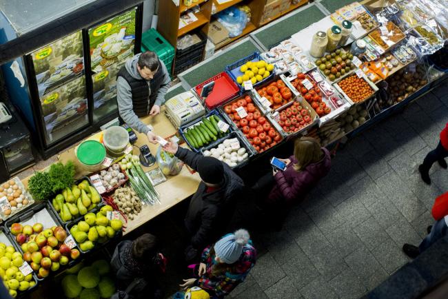 © Bloomberg. A customer pays for goods bought from a vegetable and fruit stall at an indoor market in Wroclaw, Poland, on Monday, Feb. 6, 2017. Poland’s economy expanded at the weakest pace in three years as investments dropped after a change of government ushered in the biggest political shifts in the country since the collapse of communism more than a quarter century ago. 