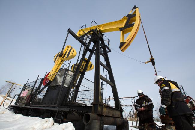 © Bloomberg. Workers inspect an oil pumping jack, also known as a 'nodding donkey' at a pumping site, operated by Rosneft PJSC, in the Samotlor oilfield near Nizhnevartovsk, Russia, on Wednesday, March 22, 2017. Russia's largest oil field, so far past its prime that it now pumps almost 20 times more water than crude, could be on the verge of gushing profits again for Rosneft PJSC. Photographer: Andrey Rudakov/Bloomberg