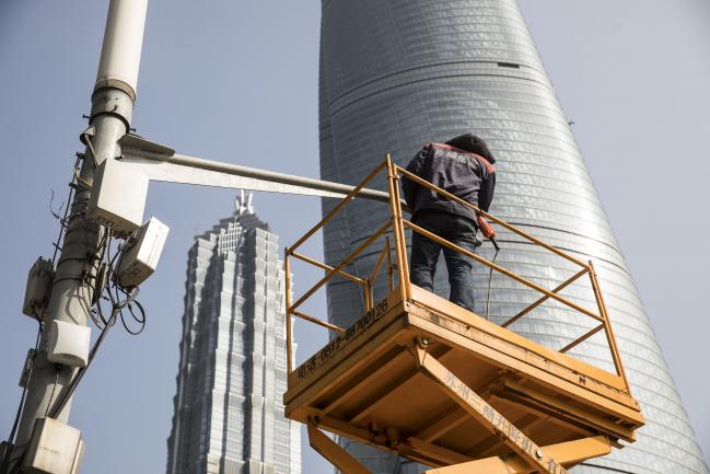 © Bloomberg. A man stands on an elevated platform while performing maintenance work on a surveillance camera in front of the Shanghai Tower, right, and the Jin Mao Tower in the Lujiazui Financial District in Shanghai, China, on Monday, Feb. 26, 2018. Xi Jinping's decision to cast aside China's presidential term limits is stoking concern he also intends to shun international rules on trade and finance, even as he champions them on the world stage. 