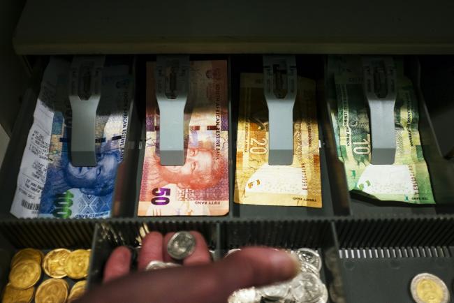 © Bloomberg. South African rand banknotes and coins sit in the till of a retail store in Johannesburg, South Africa, on Thursday, June 22, 2017. South Africa’s inflation rate rose for the first time this year in May after food-price growth quickened from the slowest pace since December 2015.