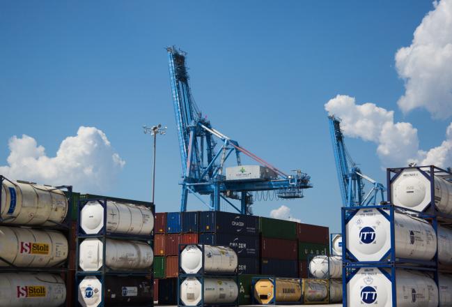 © Bloomberg. Shipping containers sit stacked in front of a gantry crane at the Port of New Orleans in New Orleans, Louisiana, U.S., on Tuesday, Sept. 18, 2018. The U.S. Census Bureau is scheduled to release trade balance figures on October 5. 