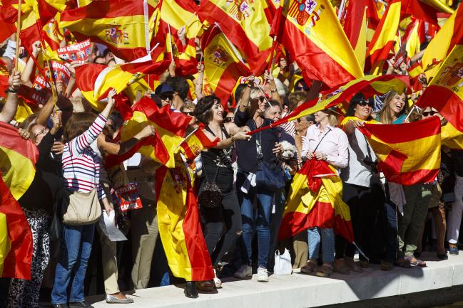 © Bloomberg. Demonstrators wave Spanish national flags in Colon Square during a protest for Spanish unity in Madrid, Spain, on Saturday, Oct. 7, 2017. Catalan President Carles Puigdemontis negotiating the text of a declaration of independence with his group's more radical partner, El Mundo newspaper has reported