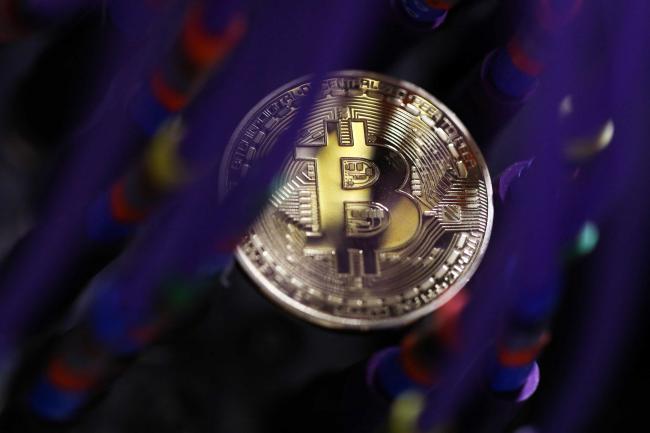 © Bloomberg. A bitcoin sits among coaxial cables inside a communications room at an office  in this arranged photograph in London, U.K., on Tuesday, Sept. 5, 2017. Bitcoin steadied after its biggest drop since June as investors and speculators reappraised the outlook for initial coin offerings.