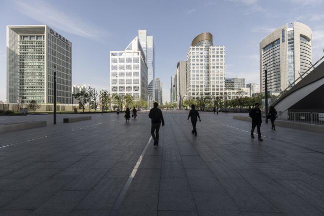 © Bloomberg. Pedestrians walk along a street in the new business district in Suzhou, China, on Tuesday, May 7, 2019. Suzhou was one of a dozen places chosen in 2018 by President Xi Jinping’s government to run a social-credit trial, which can reward or punish citizens for their behavior. The system, dubbed “Osmanthus” after the fragrant flower the city uses as an emblem, collects data on nearly two dozen metrics, including marital status, education level and social-security payments. 