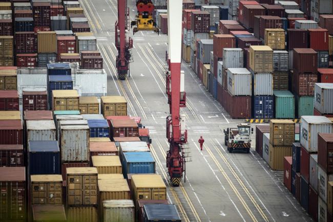 © Bloomberg. A worker walks past shipping containers sitting stacked at the Yangshan Deepwater Port, operated by Shanghai International Port Group Co. (SIPG), in Shanghai, China, on Friday, May 10, 2019. The U.S. hiked tariffs on more than $200 billion in goods from China on Friday in the most dramatic step yet of President Donald Trump's push to extract trade concessions, deepening a conflict that has roiled financial markets and cast a shadow over the global economy. 