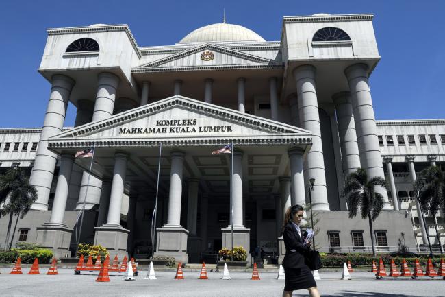 © Bloomberg. A pedestrian walks past the Kuala Lumpur Courts Complex in Kuala Lumpur, Malaysia, on Monday, Jan. 7, 2019. A Malaysian court denied bail for Roger Ng, a former Goldman Sachs Group Inc. banker who was charged in the country for his role in 1MDB deals while facing extradition to the U.S. for similar allegations. 