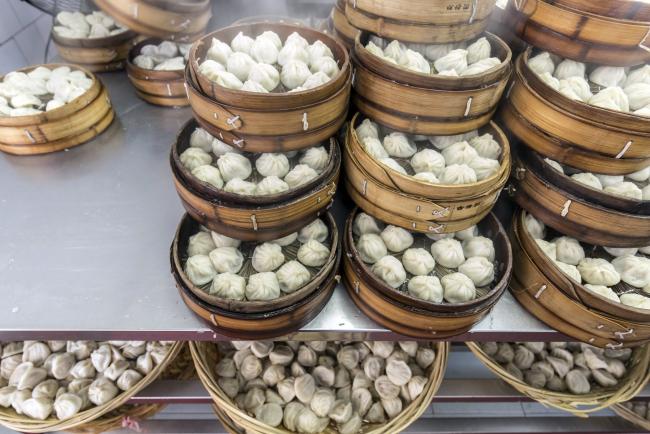 © Bloomberg. Bamboo baskets of freshly-steamed xiaolongbao dumplings sit in the kitchen at the Guyi Garden Restaurant in Shanghai, China, on Sunday, Jan. 27, 2019. An early Chinese New Year holiday this year will help temporarily shield food and non-alcoholic beverage producers from the weak economy, according to China International Capital Corp. Photographer: Qilai Shen/Bloomberg