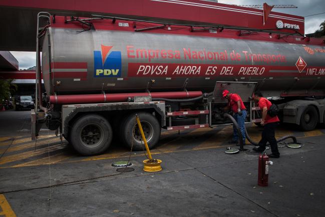 © Bloomberg. Employees work at a Petroleos de Venezuela SA (PDVSA) gas station in Caracas, Venezuela, on Thursday, March 23, 2017. Residents of Venezuela's capital awoke to long lines of cars at gas stations amid rumors that fuel supplies in the nation with the world's largest oil reserves are running out.