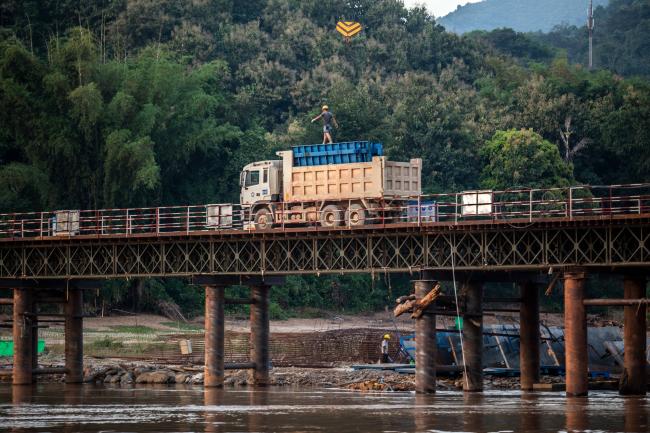 © Bloomberg. A worker walks atop a lorry on the construction site of the Ban Ladhan Railway bridge, a section of the China-Laos Railway built by the China Railway Group Ltd., on the Mekong River in Ban Ladhan, Luang Prabang province, Laos, on Thursday, Oct. 18, 2018. China's Belt and Road initiative plans to connect Southeast Asian countries with the southwest region of Yunnan through a series of high-speed railways. There are three routes planned: a central one that runs through Laos, Thailand and Malaysia to reach Singapore; a western route through Myanmar; and an eastern one through Vietnam and Cambodia. Photographer Taylor Weidman/Bloomberg