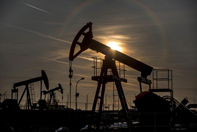 © Bloomberg. The sun sets beyond oil pumping units.