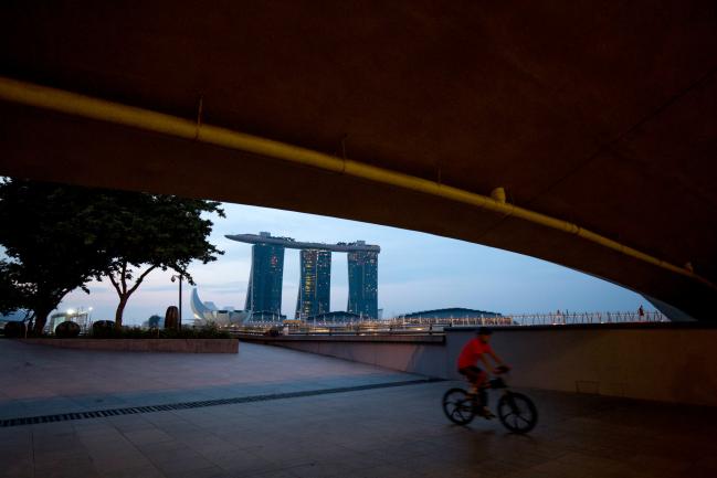 © Bloomberg. A cyclist rides underneath a bridge at the Marina Bay waterfront as the Marina Bay Sands hotel and casino stands in the background in Singapore, on Sunday, June 10, 2018. U.S. President Donald Trump and North Korean leader Kim Jong Un will hold their historic Singapore summit at the Capella Hotel on the city-states Sentosa Island on June 12. 