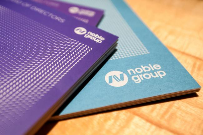 © Bloomberg. Noble Group Ltd. booklets sit on a table before a news conference during an investor day in Singapore, on Monday, Aug. 17, 2015.  