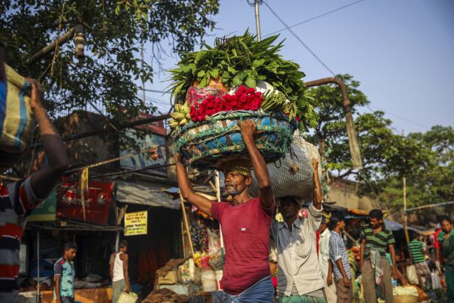 © Bloomberg. A man carries a basket of flowers on his head as he walks through the Mullick Ghat flower market in Kolkata, India, on Tuesday, April 30, 2019. Prime Minister Narendra Modi is seeking a re-election bid in national elections that began April 11 and takes place in seven phases through May 19. 