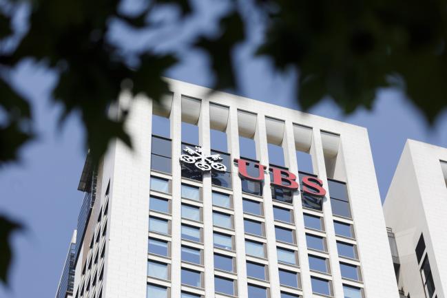 © Bloomberg. The UBS Group AG logo sits on the bank's skyscraper offices in Frankfurt, Germany, on Tuesday, July 17, 2018. Frankfurt's efforts to attract bankers escaping Brexit are in danger of losing momentum. 