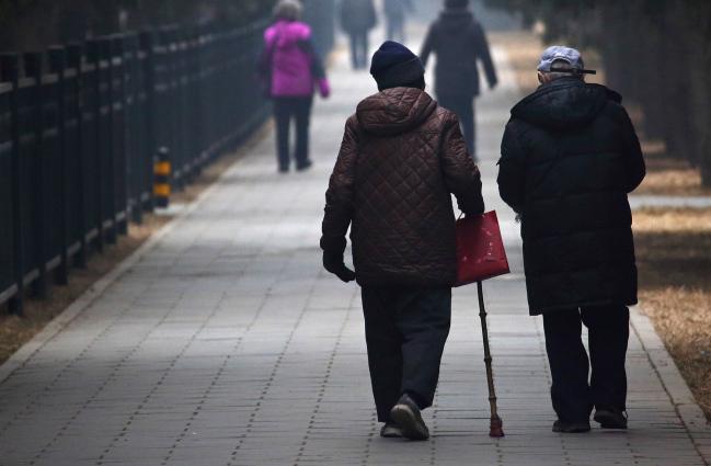 © Bloomberg. People walk through Tiantan Park in Beijing.