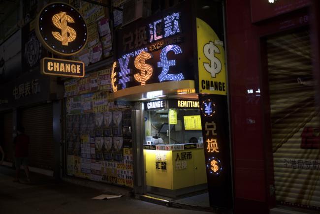 © Bloomberg. Currency symbols are illuminated at a currency exchange store at night in the Mong Kok district of Hong Kong, China.