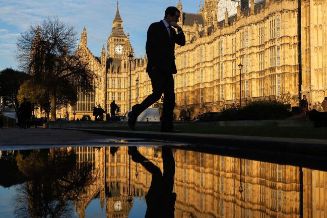 © Bloomberg. A man passes a puddle reflecting Elizabeth Tower, commonly referred to as Big Ben, and Houses of Parliament in London, U.K. on Tuesday Jan. 17, 2017. The U.K. is likely to pull out of the European Union's single market for goods and services and seek a completely new trading relationship with the bloc, Prime Minister Theresa May will say Tuesday as she sets out her plan for Brexit.
