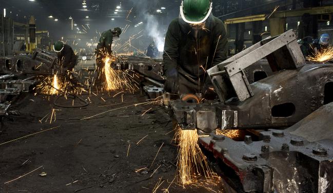 © Bloomberg. Workers use grinders to smooth down the welded joints for railroad suspension parts at the Columbus Castings facility. 