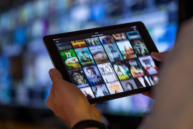 © Bloomberg. A selection of Netflix Inc. original content sits displayed in the Netflix app on an Apple Inc. iPad tablet device in this arranged photograph in London, U.K., on Monday, Aug. 20, 2018. The NYSE FANG+ Index is an equal-dollar weighted index designed to represent a segment of the technology and consumer discretionary sectors consisting of highly-traded growth stocks of technology and tech-enabled companies. Photographer: Jason Alden/Bloomberg