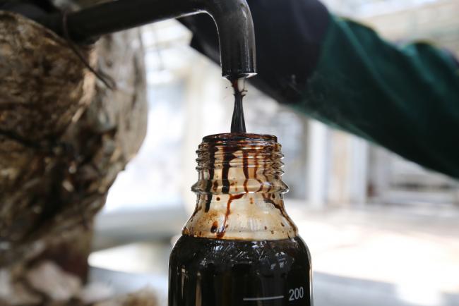 © Bloomberg. An employee collects a sample of crude oil for laboratory testing.