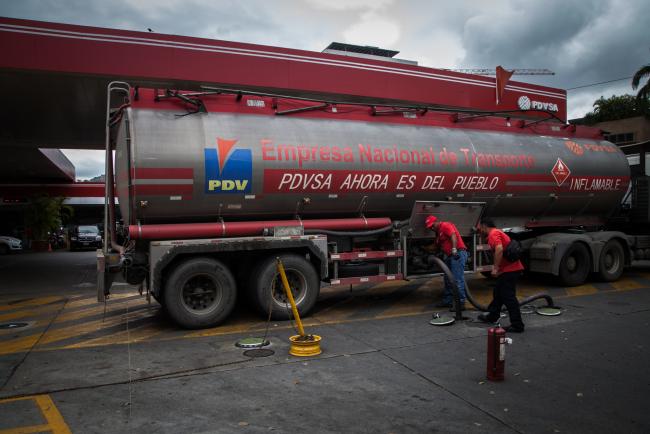 © Bloomberg. Employees work at a Petroleos de Venezuela SA (PDVSA) gas station in Caracas. 