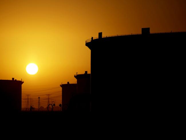 © Bloomberg. The sun sets beyond crude oil storage tanks at the Juaymah tank farm at Saudi Aramco's Ras Tanura oil refinery and oil terminal in Ras Tanura, Saudi Arabia. Photographer: Simon Dawson/Bloomberg