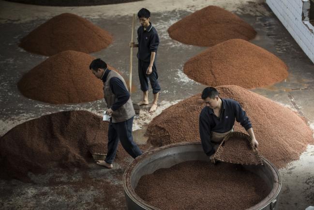 © Bloomberg. Employees scoop sorghum into vats at the Kweichow Moutai Co. distillery in the town of Maotai in Renhuai, Guizhou province, China, on Thursday, Dec. 14, 2017. Moutai baijiu's fiery flavor and potential to appreciate in price is driving blistering demand. That in turn has pushed its market value to more than $145 billion, well past British whisky giant Diageo Plc.