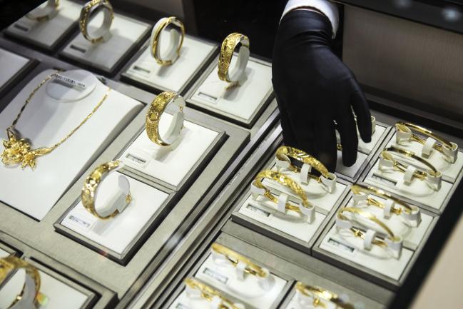 © Bloomberg. An employee arranges gold bracelets at a Chow Tai Fook store in Shanghai.