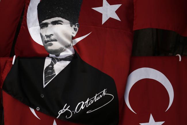 © Bloomberg. A child stands behind a Turkish flag decorated with the image of Kemal Ataturk. 