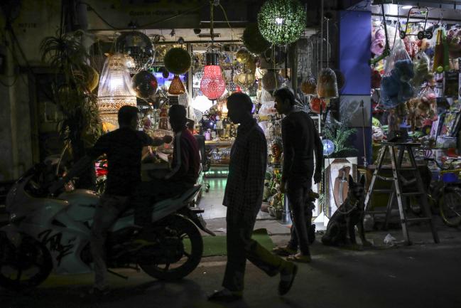 © Bloomberg. Pedestrians are silhouetted as they walk past an electronics store selling lights in Raghunath Market at night in Jammu, Jammu and Kashmir, India, on Wednesday, Nov. 15, 2017. The head of treasury at State Bank of India is betting against the street. Inflation will stay anchored after the recent uptick, giving the central bank room to cut interest rates and bonds to rally, C. Venkat Nageswar said. Photographer: Dhiraj Singh/Bloomberg