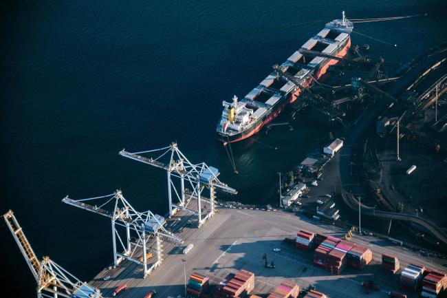 © Bloomberg. A ship sits docked alongside a coal depot at the GCT Deltaport container terminal in this aerial photograph taken above Delta, British Columbia, Canada, on Thursday, Sept. 6, 2018. The U.S. and Canada continued to look for ways to bridge their differences as talks resumed to update the North American Free Trade Agreement, with Ottawa insisting it won't sign a bad deal. 