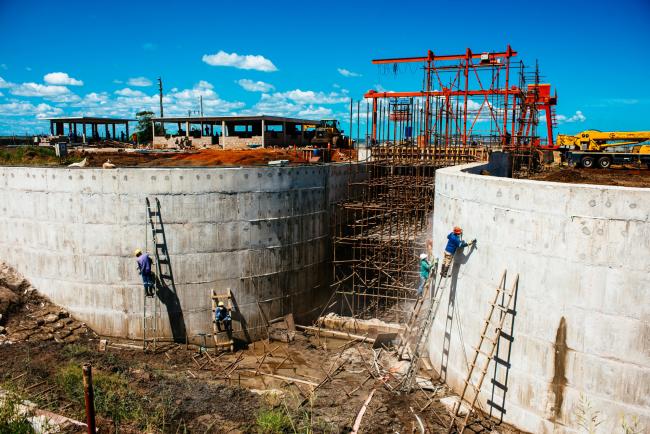 © Bloomberg. Workers build a hydro pumping station which will supply water from the Limpopo river to nearby rice farms owned by Wanbao Grains & Oils Co., a Chinese company, in the Limpopo Valley near Xai Xai village, Mozambique, on Friday, March 24, 2017. The granaries and surveillance cameras in this corner. 