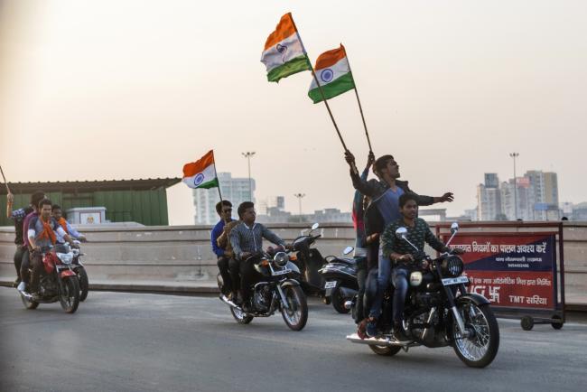 © Bloomberg. Supporters of the Samajwadi Party (SP) carry Indian national flags while riding motorcycles in Lucknow, Uttar Pradesh, India, on Tuesday, Feb. 14, 2017. The success of the Samajwadi government's infrastructure projects has allowed them to hijack Indian Prime Minister Narendra Modi's mantra of development. Now it's possible the Bharatiya Janata Party (BJP) could lose India's most important state election, that began on Feb. 11., endangering further economic reforms and sapping Modi's momentum ahead of the 2019 national elections. Photographer: Prashanth Vishwanathan/Bloomberg