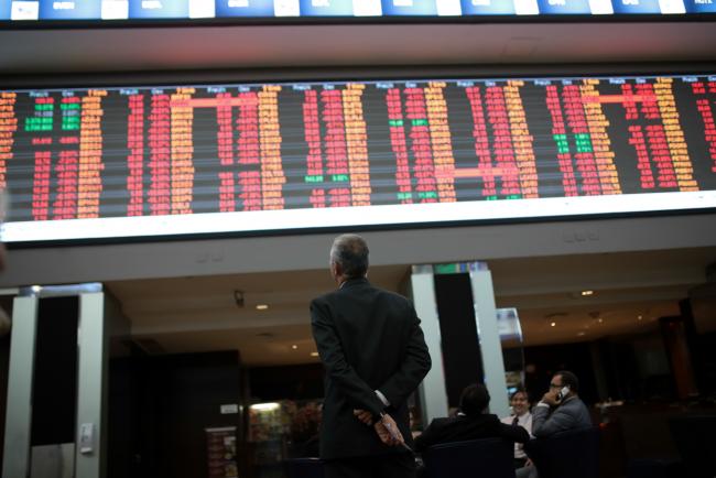 © Bloomberg. A visitor views the electronic board displaying stock activity at the Brasil Bolsa Bacao (B3) stock exchange in Sao Paulo, Brazil. Photographer: Patricia Monteiro/Bloomberg