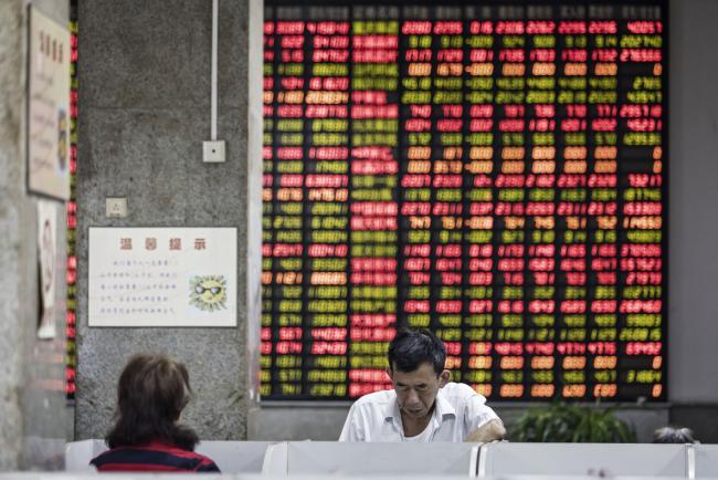 © Bloomberg. Investors stand in front of an electronic stock board at a securities brokerage in Shanghai, China. Photographer: Qilai Shen/Bloomberg