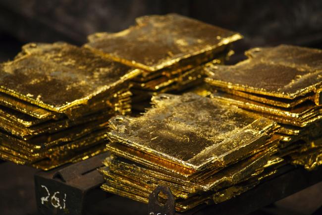 © Bloomberg. Solid gold slabs sit in piles following the electro refining process to remove impurities at the Rand Refinery Ltd. plant in Germiston, South Africa, on Wednesday, Aug. 16. 2017. Established by the Chamber of Mines of South Africa in 1920, Rand Refinery is the largest integrated single-site precious metals refining and smelting complex in the world, according to their website.