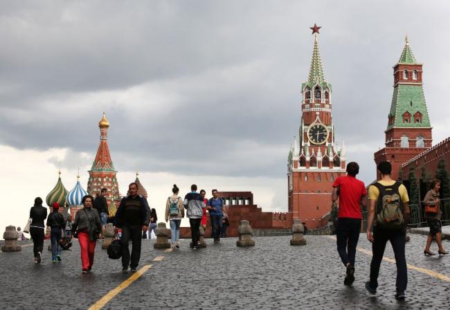© Bloomberg. The Kremlin clock sits on the Spasskaya tower, center, near St. Basil's cathedral, left, on Red Square in Moscow, Russia, on Wednesday, July 5, 2017. U.S. officials, including Brett McGurk, the U.S. envoy for the coalition to fight the Islamic State, have been quietly meeting with Russian counterparts for weeks to lay the groundwork for cooperation. 