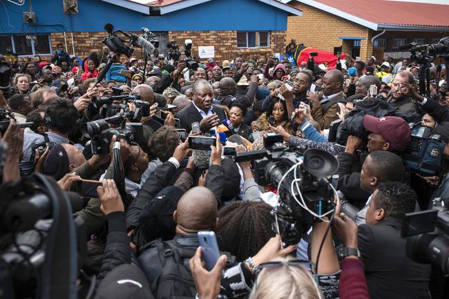 © Bloomberg. Cyril Ramaphosa, South Africa's president, center, is mobbed by supporters and members of the media as he arrives to cast his vote at a polling station during the general election in Soweto, South Africa, on Wednesday, May 8, 2019. While opinion polls point to the ruling African National Congress extending its quarter-century monopoly on power in Wednesdays vote, Ramaphosa needs a decisive win to quell opposition in his faction-riven party to push through reforms needed to spur growth in Africas most-industrialized economy. Photographer: Waldo Swiegers/Bloomberg