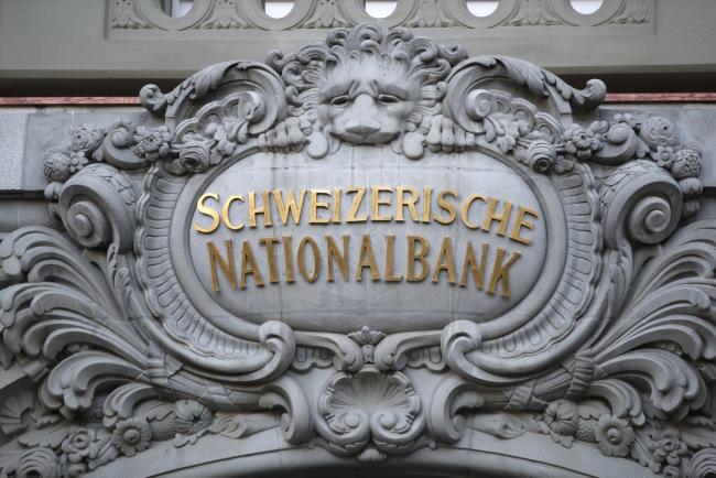 © Bloomberg. A Swiss National Bank (SNB) logo sit above the the entrance to the central bank in Bern, Switzerland, on Thursday, Dec. 13, 2018. The Swiss National Bank cut its inflation forecast and showed no inclination of moving off its crisis-era settings, citing the franc’s strength and mounting global risks. Photographer: Stefan Wermuth/Bloomberg