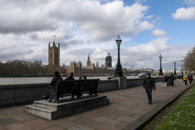 © Bloomberg. Pedestrians walk along the Thames Path in view of the Houses of Parliament in London, U.K., on Thursday, April 4, 2019. Theresa May's government holds intensive talks with Jeremy Corbyn's opposition Labour Party in search of a compromise position on the U.K.’s future ties to the EU. 