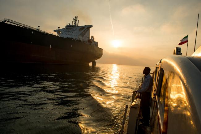 © Bloomberg. A support vessel flying an Iranian national flag sails alongside the oil tanker 'Devon' as it prepares to transport crude oil to export markets in Bandar Abbas, Iran. Photographer: Ali Mohammadi/Bloomberg
