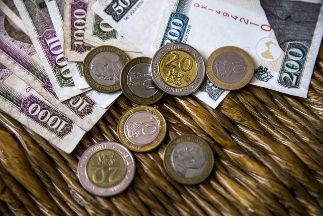 © Bloomberg. Kenyan shilling banknotes and coins sit arranged at a market stall in Mombasa, Kenya, on Thursday, Nov. 23, 2017. The country’s Treasury has already cut this year’s growth target to 5 percent from 5.9 percent as the protracted election furor damped investment and a drought curbed farm output. 