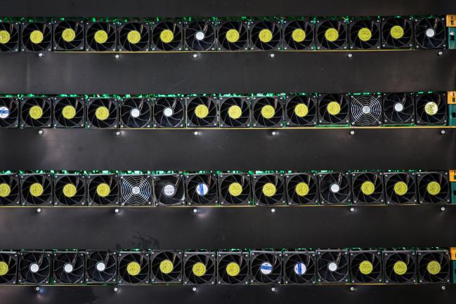 © Bloomberg. Cryptocurrency mining rigs sit on racks at a Bitfarms facility in Saint-Hyacinthe, Quebec, Canada, on Thursday, July 26, 2018.  