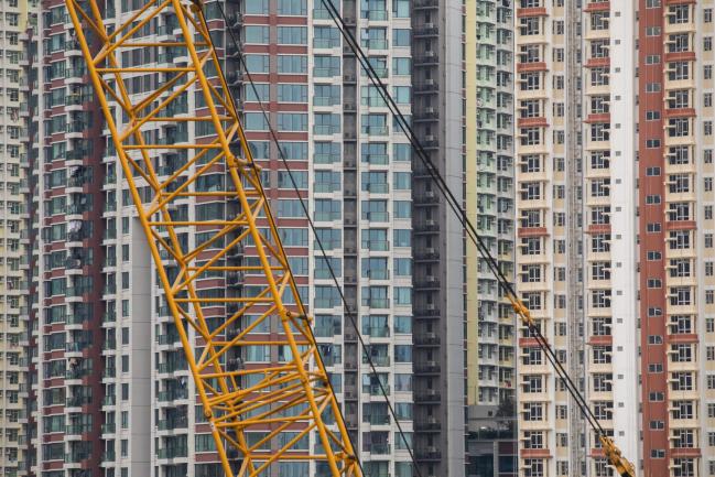 © Bloomberg. A crane stands at a construction site at the former Kai Tak airport area in front of residential buildings in Hong Kong, China, on Saturday, July 21, 2018. Hong Kong's property market has a habit of humbling the bears, shattering predictions that the laws of gravity must eventually prevail. Photographer: Paul Yeung/Bloomberg