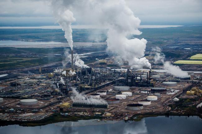 © Bloomberg. Steam rises from the Syncrude Canada Ltd. upgrader plant in this aerial photograph taken above the Athabasca oil sands near Fort McMurray, Alberta, Canada, on Monday, Sept. 10, 2018. While the upfront spending on a mine tends to be costlier than developing more common oil-sands wells, their decades-long lifespans can make them lucrative in the future for companies willing to wait. Photographer: Ben Nelms/Bloomberg
