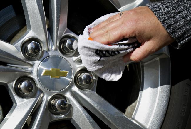 © Bloomberg. Customer Tracy Boehm wipes the wheel of a 2013 General Motors Co. (GM) Chevrolet Equinox vehicle after having it washed at Green car dealership in Peoria, Illinois, U.S., on Wednesday, March 28, 2012. 