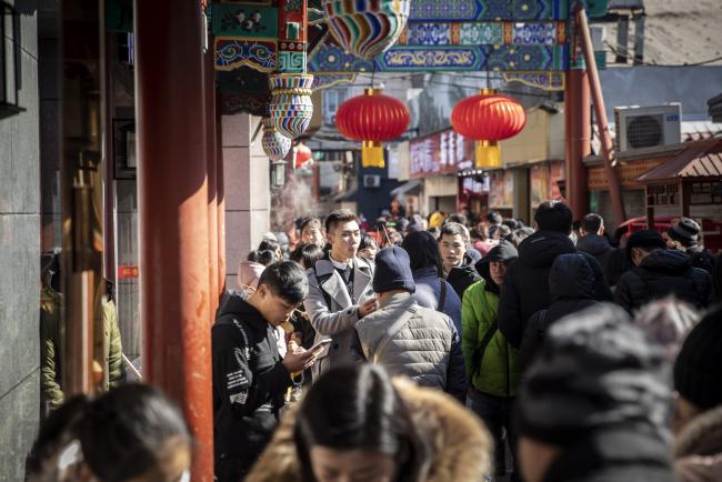 © Bloomberg. Pedestrians walk past stores in Beijing, China, on Friday, Feb. 15, 2019. With a continued slowdown in industrial output and consumption, a further deceleration in China's economy will hurt demand for imported goods. Photographer: Qilai Shen/Bloomberg